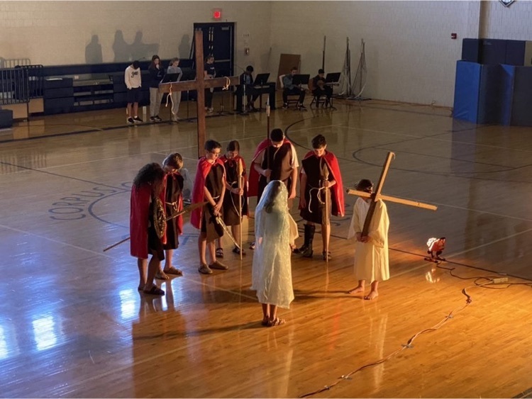 students portraying the living stations of the cross in gymnasium