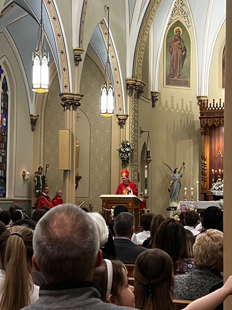 A bishop wearing red is reading to the church congregation