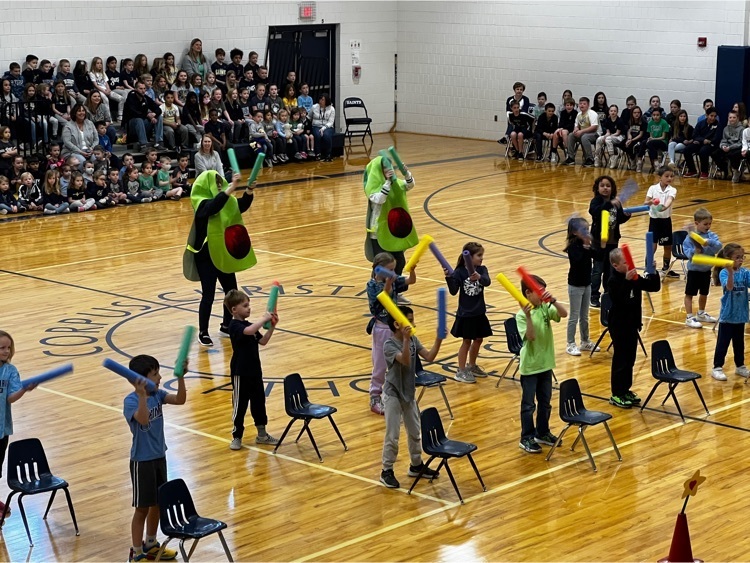 students standing behind chairs with noodles and two teachers dressed in avocado costume
