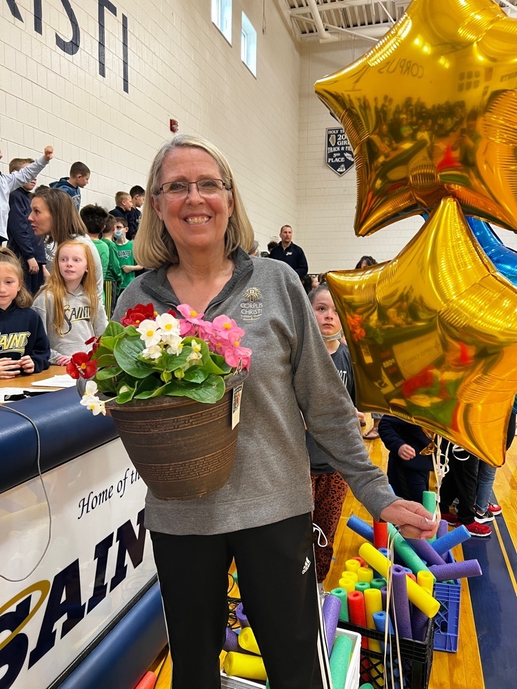 teacher smiling with flowers and star shaped balloons