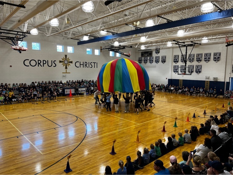 students standing in middle lifting large parachute