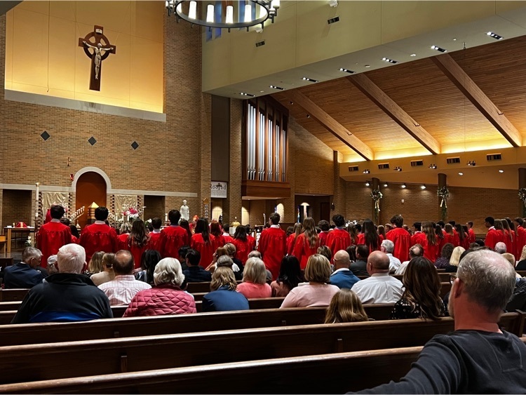 students in red robes standing In church facing the altar