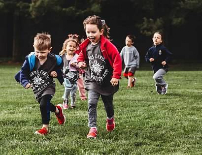 girl in red jacket running alongside boy in gray tshirt