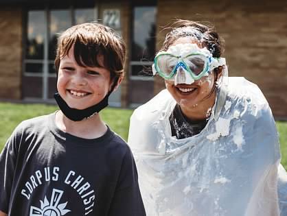 student standing next to principal wearing goggles and poncho